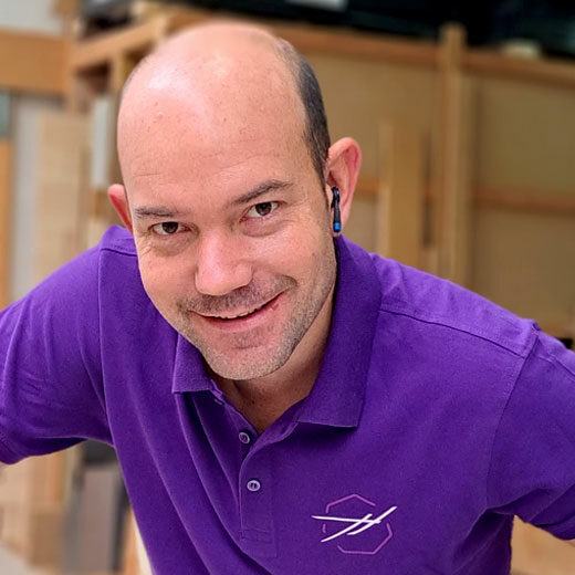 Portrait d'Yves PEDEN souriant avec un tee-shirt à la couleur mauve et logo HEPTAGONE